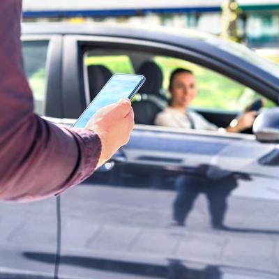 A person is on the phone while a Rideshare driver approaches for pickup.