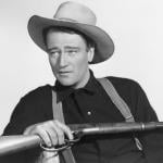 John Wayne holding a rifle in a publicity photo for the movie Shepherd of the Hills.