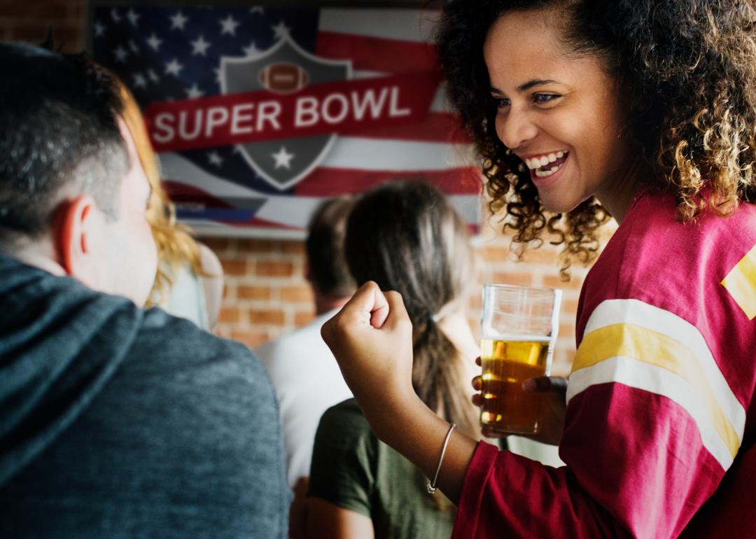 People cheering with Super Bowl banner in background.