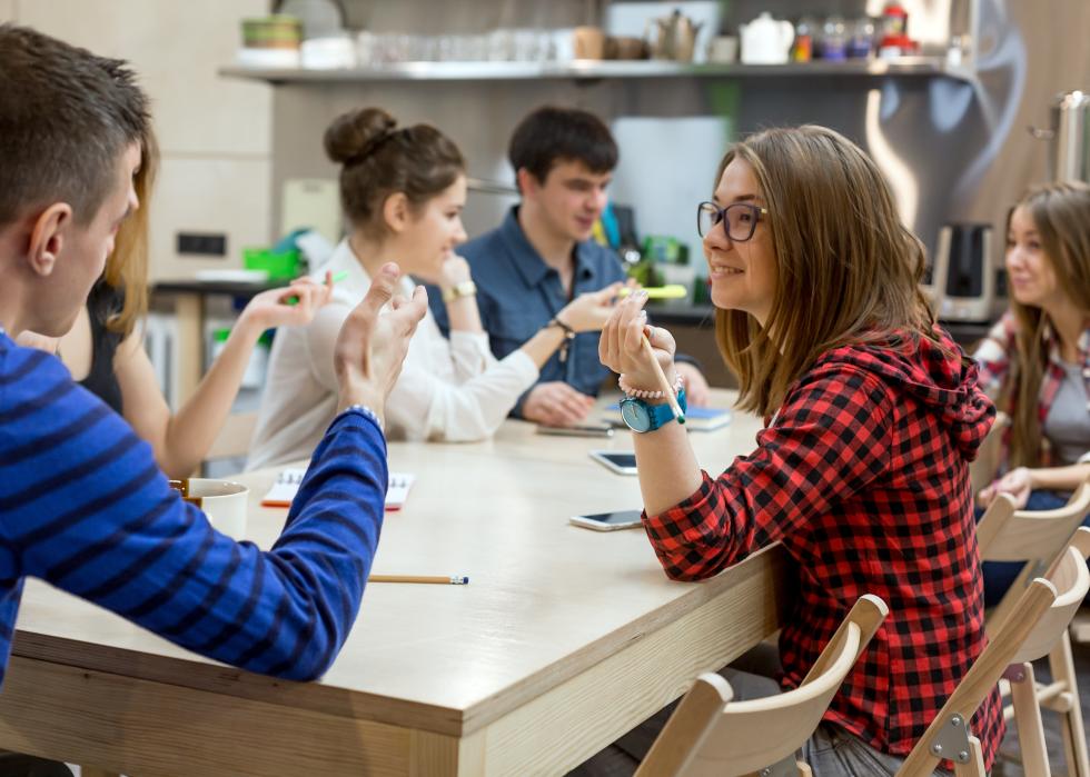 Group of students chatting around a wood table.