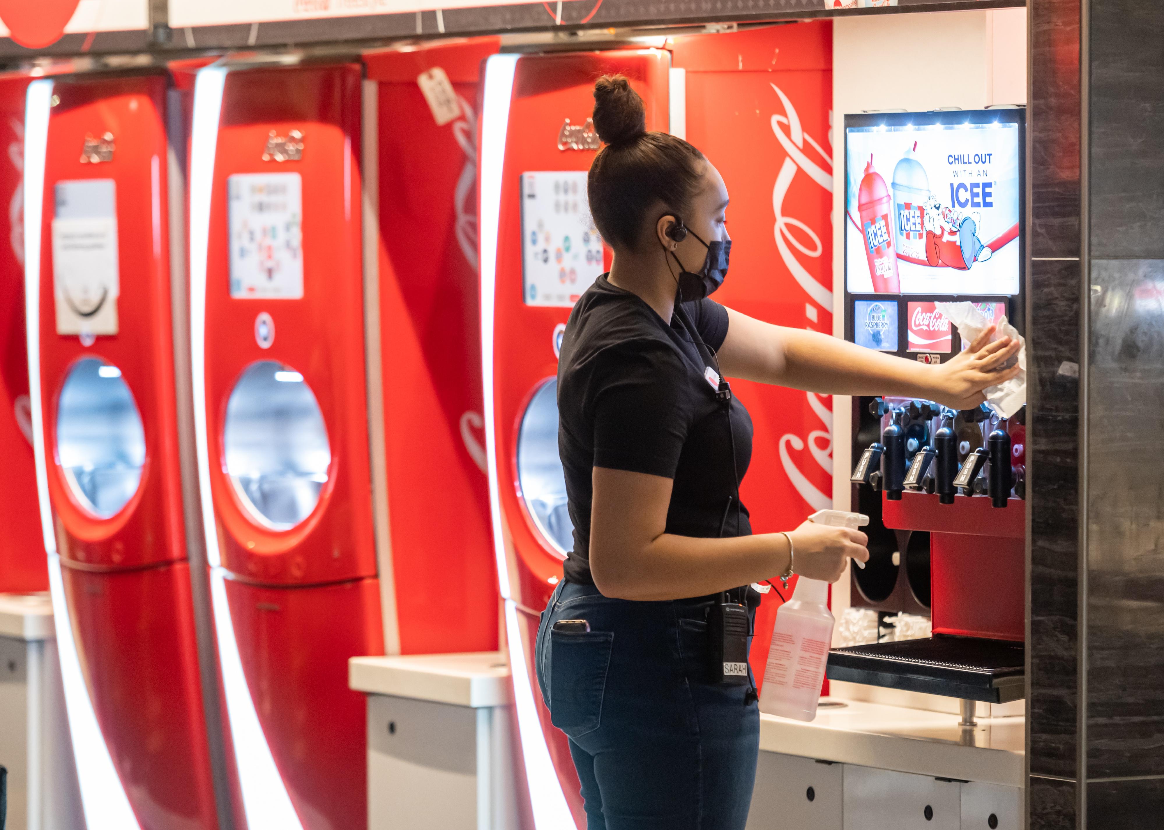 A woman cleaning a soda fountain machine.