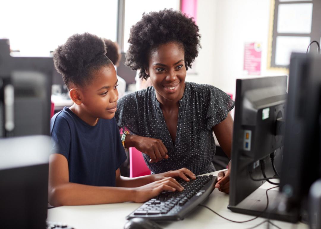 A tutor helps a student at a computer.