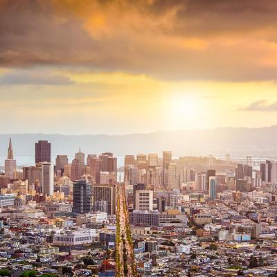 View of San Francisco city skyline at dawn with golden orange clouds above.