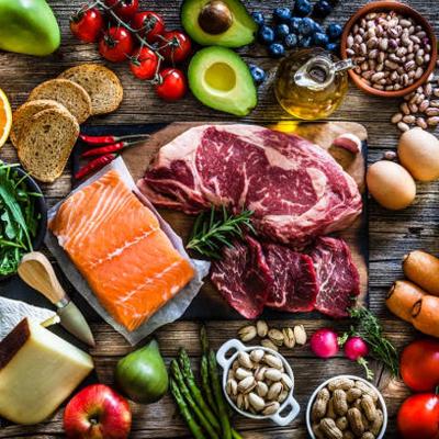 Overhead view of protein-rich foods including red meat, salmon, cheese and a wide range of fruits and vegetables.