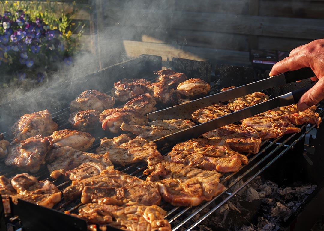 Different types of meat like steak, chicken, and chops being carefully grilled.