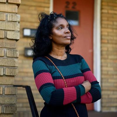 Portrait of Diane Lewis standing in front the apartment where she grew up in Connecticut. 