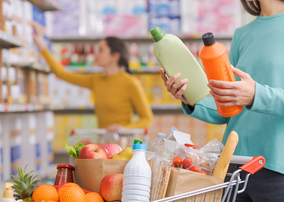 Person comparing bottles of detergent in market.