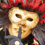 Close view of person wearing gold feathered Venetian mask at festival.