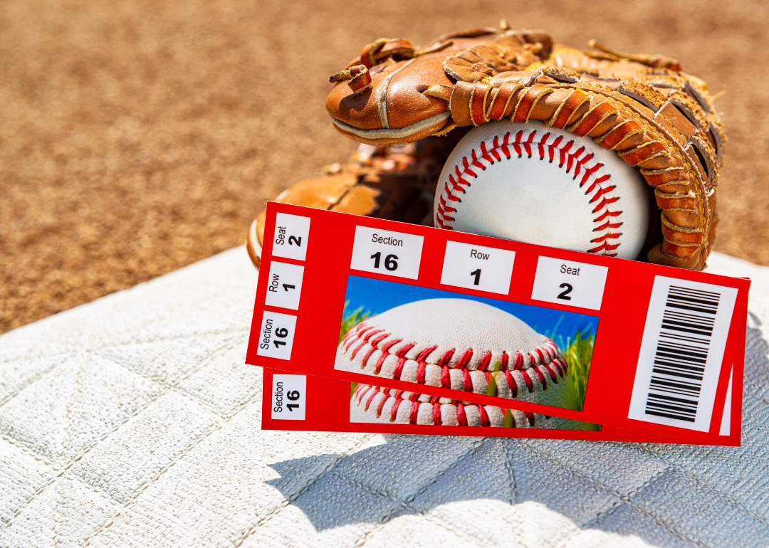 A pair of baseball game ticket stubs on second base with a ball and glove.