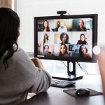 Businesswoman talks with colleagues during virtual meeting.