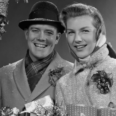 Couple wearing winter coats and carrying Christmas packages in the 1950s.